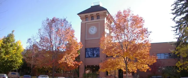 A brick clock tower in Durango, Colorado, framed by autumn trees